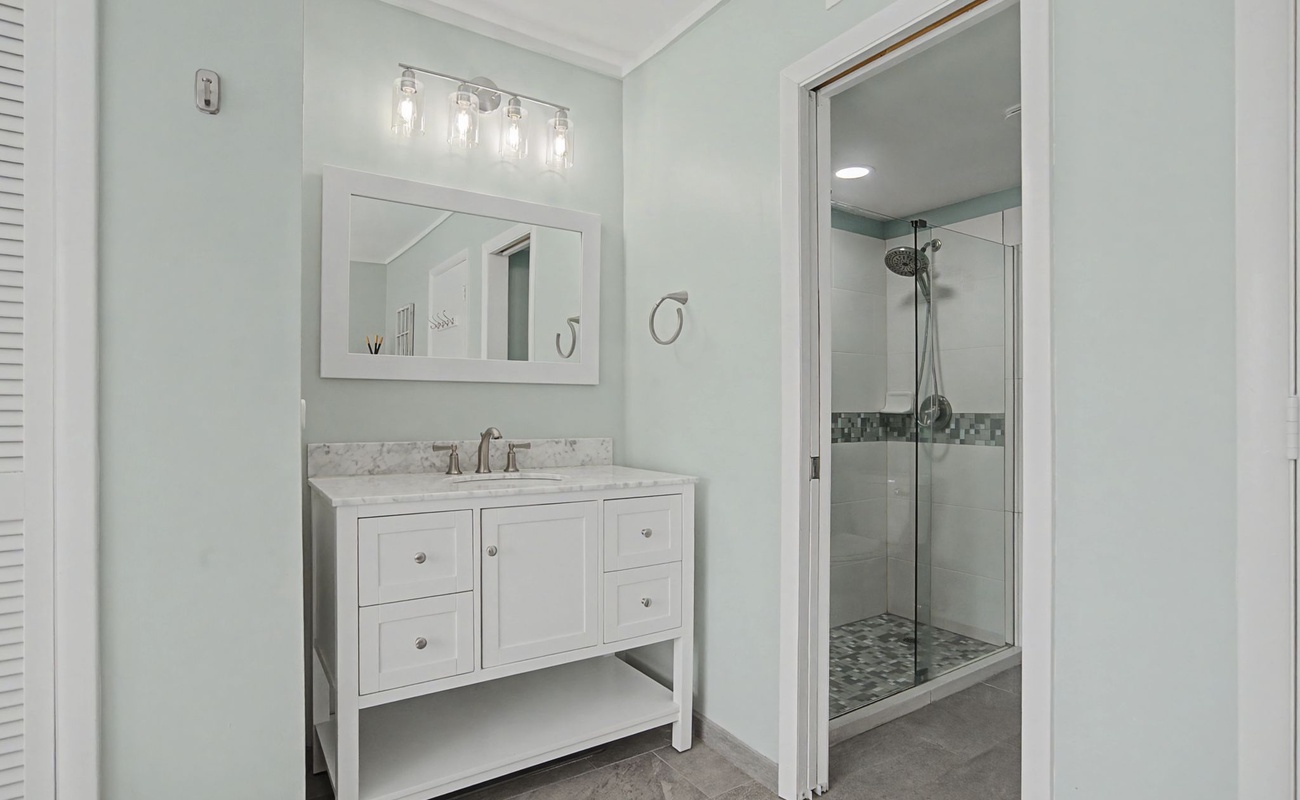 Step into your serene bathroom sanctuary with elegant marble vanity, rainfall shower, and soothing coastal colors that invite relaxation after your day.