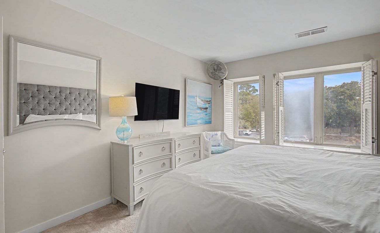 Wake up to serene forest views in your elegant bedroom, complete with plush bedding and peaceful natural light streaming through windows.