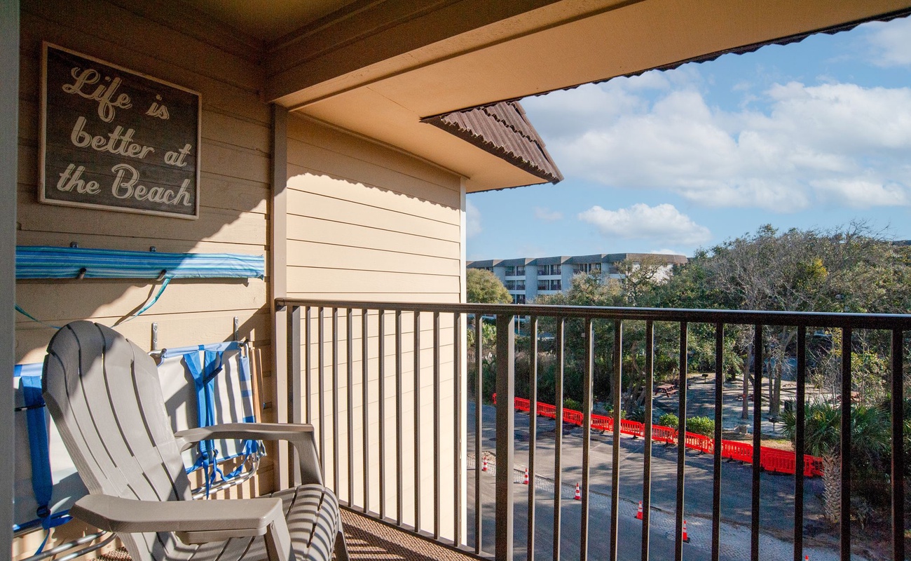 Sip your morning coffee on your private balcony, with comfy chairs and a charming beach sign setting the perfect coastal mood.