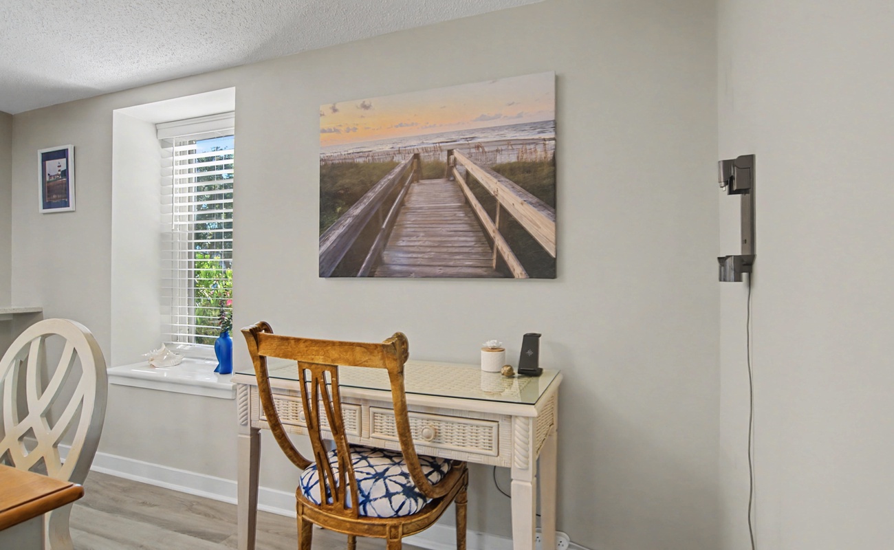 Your dedicated workspace features a charming wooden desk, comfortable chair, and inspiring beach boardwalk artwork to keep you motivated.