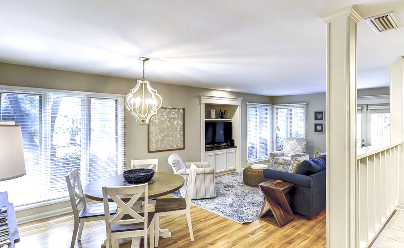 Unwind in your bright open living space with gleaming hardwood floors, elegant chandelier, and cozy seating perfect for relaxing evenings.