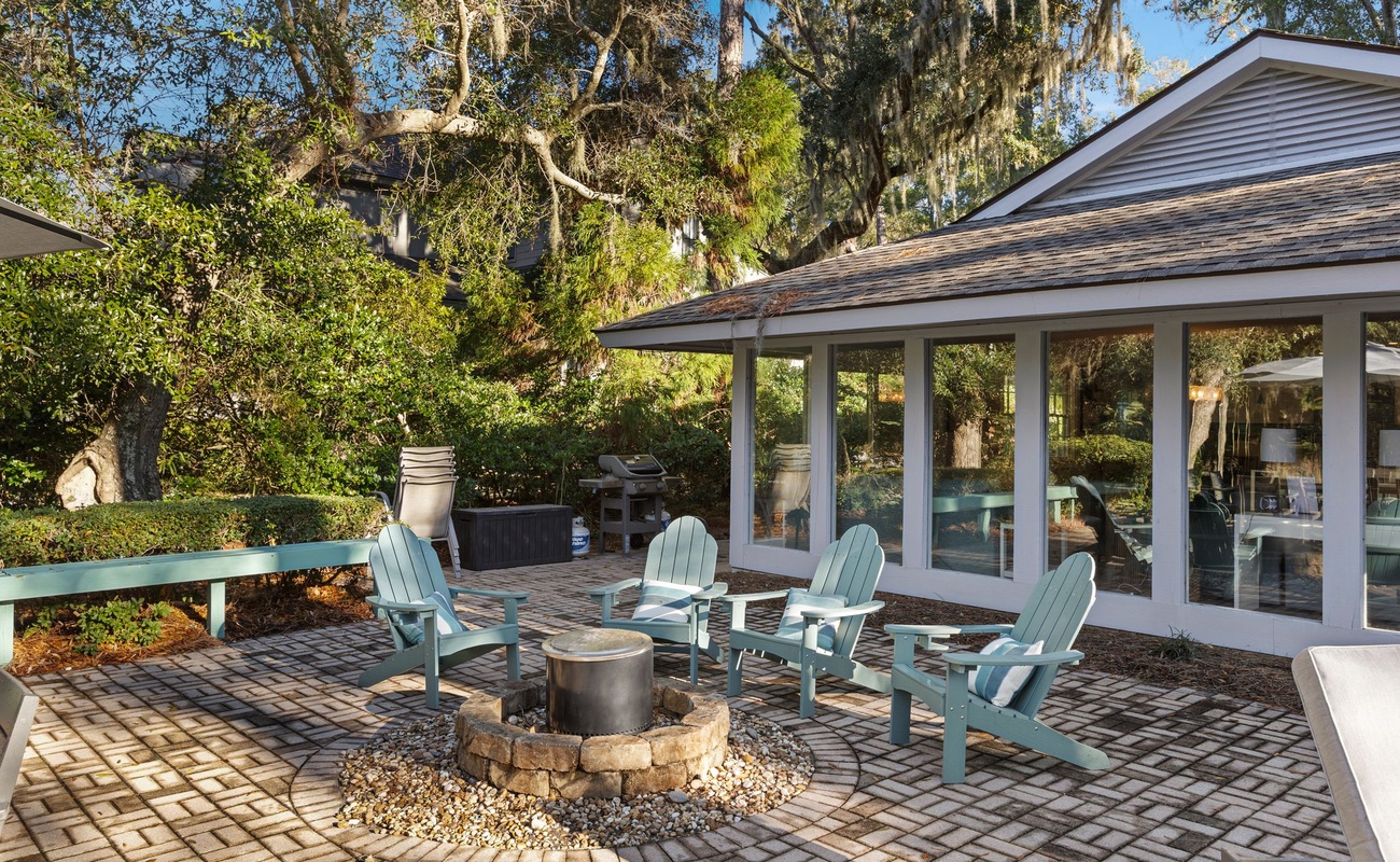 Gather around the fire pit on this charming paver patio, surrounded by mature trees and comfortable seating.