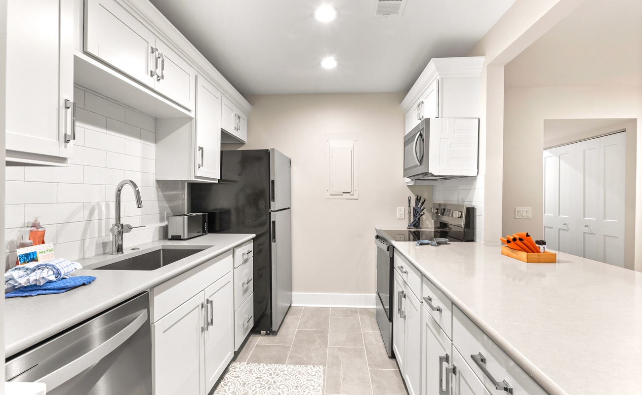 Your fully equipped modern kitchen features crisp white cabinetry, granite countertops, and stainless steel appliances for effortless meal preparation.