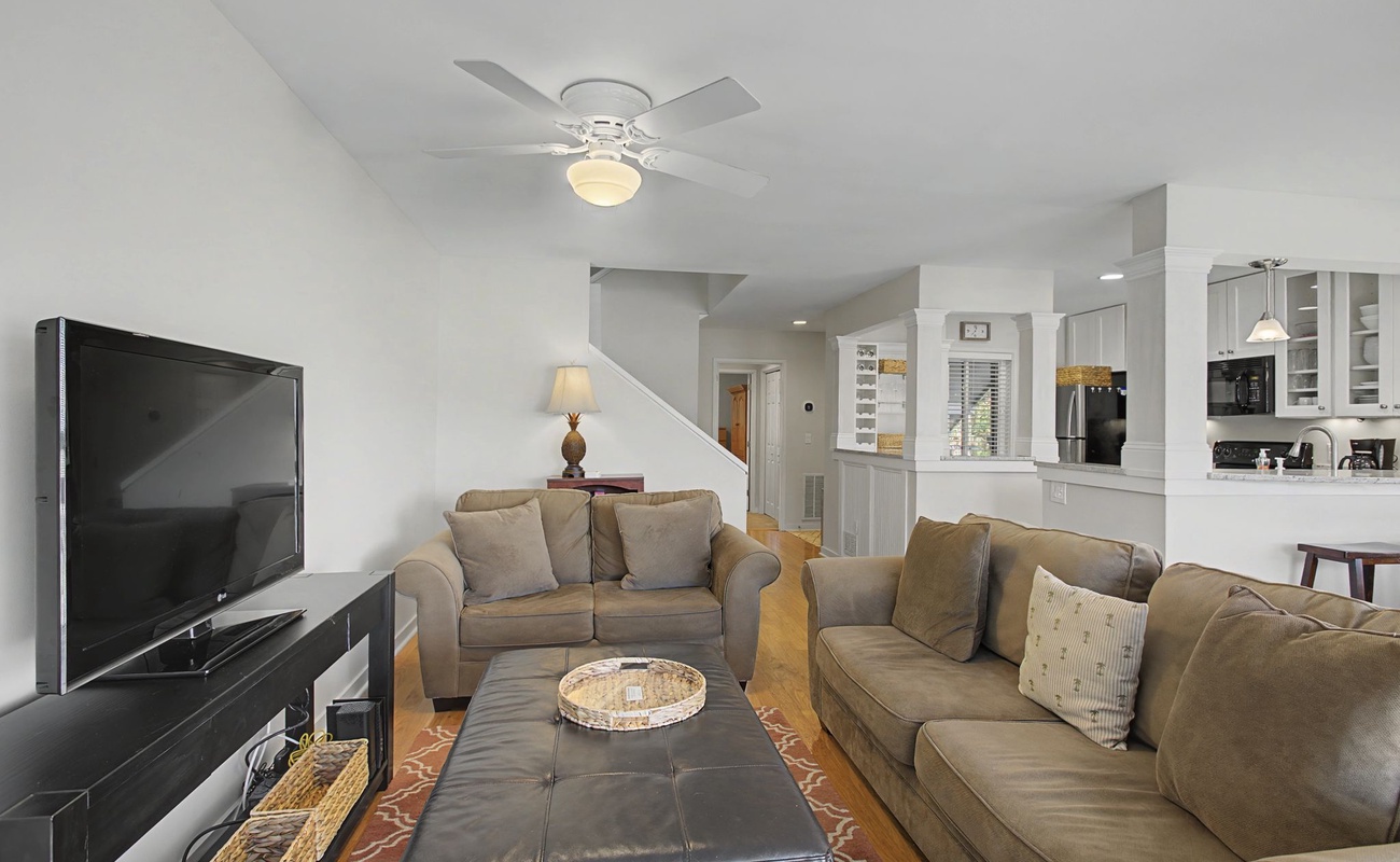 Relax in your spacious living room with plush seating, entertainment center, and open flow to the kitchen.