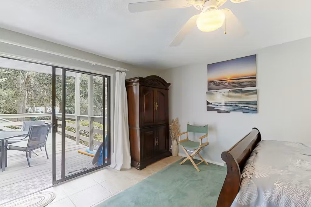 Wake up in your serene bedroom where ocean art and patio doors frame peaceful garden views, creating the perfect retreat.