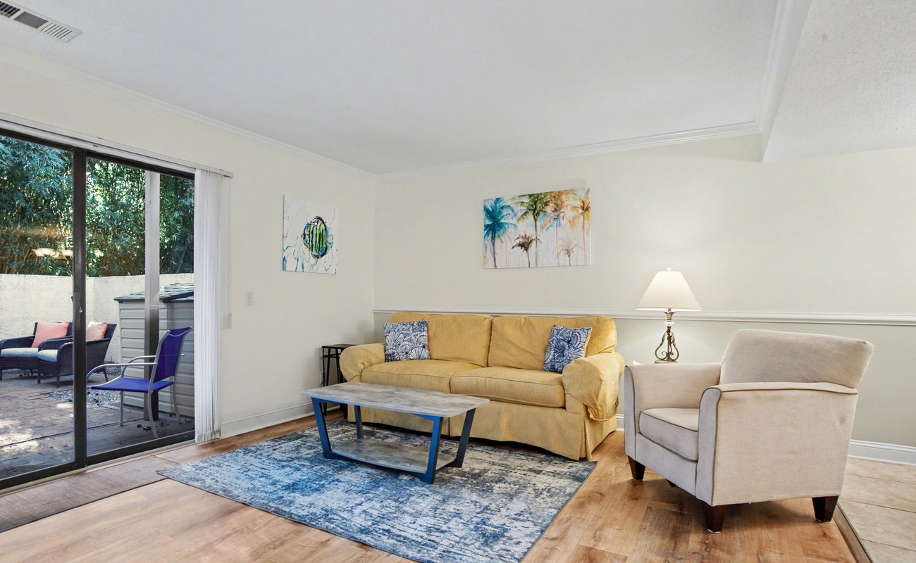 Unwind in your bright living room with comfortable seating and tropical artwork, opening to your private patio retreat.
