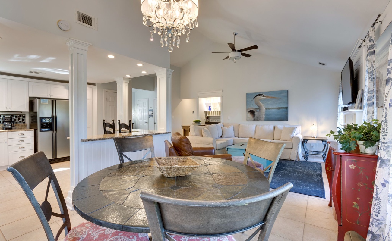 Your open-concept living space flows beautifully from dining to kitchen, with elegant crystal chandelier lighting and comfortable seating for memorable meals.