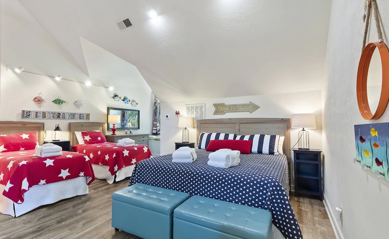 Step into your cheerful nautical-themed bedroom where starry red bedding and navy stripes create the perfect coastal retreat for restful nights.