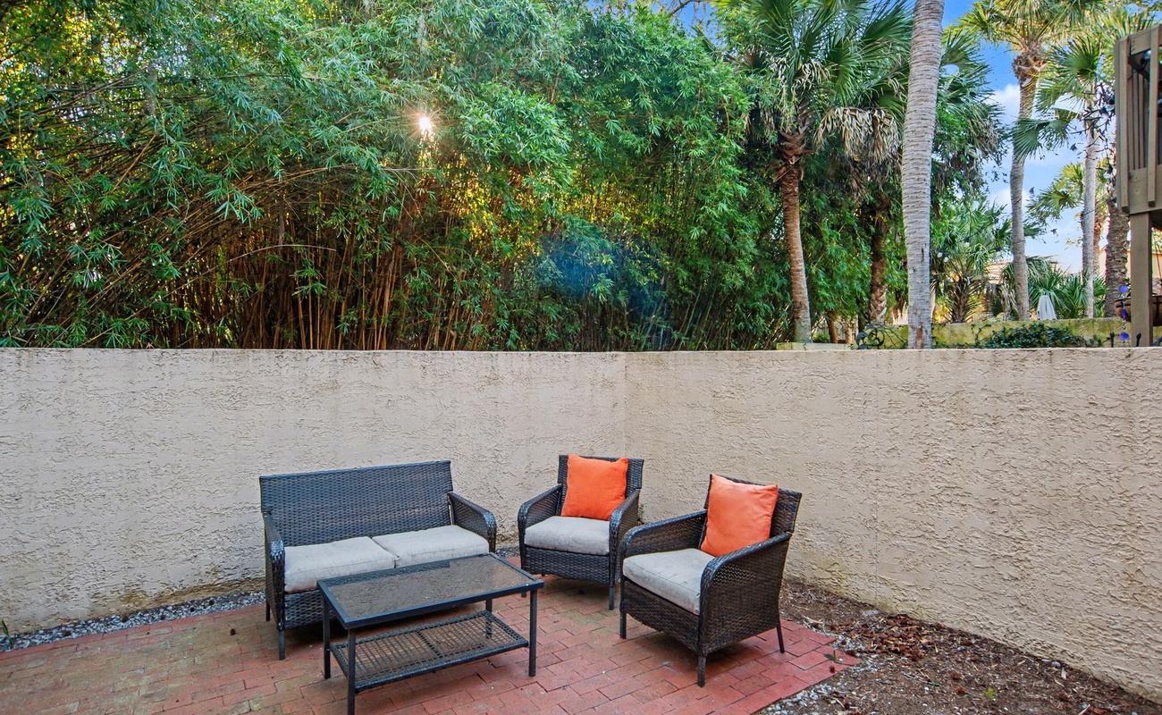 Step outside to your private patio where wicker seating awaits beneath swaying palms and tropical greenery.
