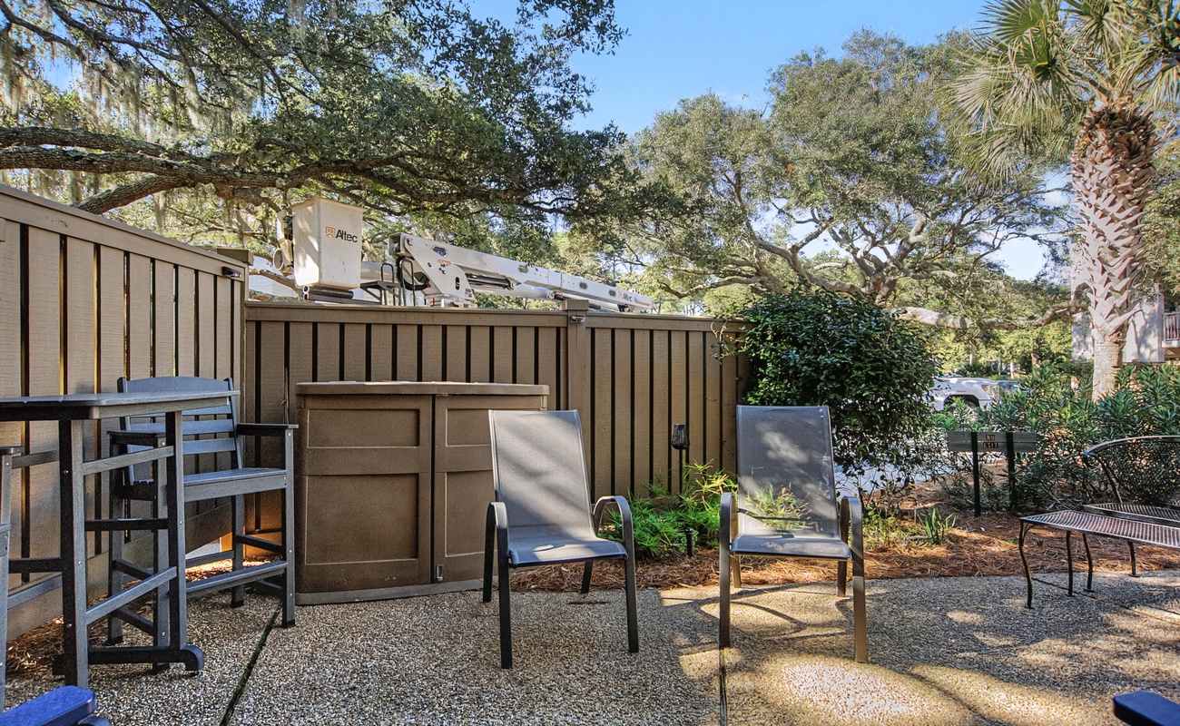 Relax in your private outdoor space with comfortable seating surrounded by lush greenery and mature trees.