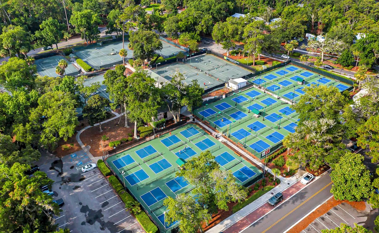 Aerial view of tennis facilities featuring multiple courts surrounded by lush tree-lined neighborhood with convenient parking access.