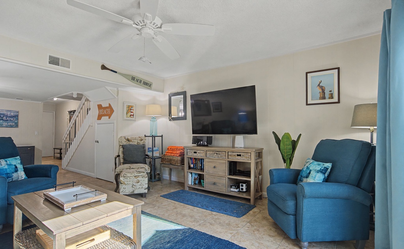 Relax in your bright living room with coastal blues, comfy seating, and entertainment center - perfect for unwinding after beach days.
