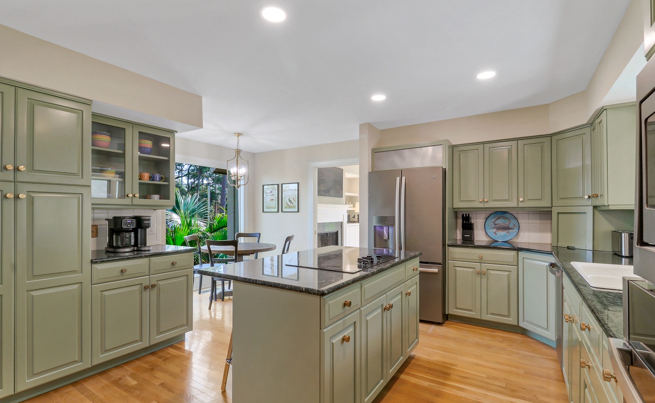 Cook with ease in this spacious kitchen featuring sage cabinets, granite counters, and stainless appliances - perfect for preparing memorable meals.