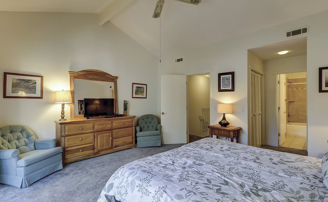 Your spacious bedroom features vaulted ceilings, classic furnishings, and a cozy reading chair for ultimate relaxation.