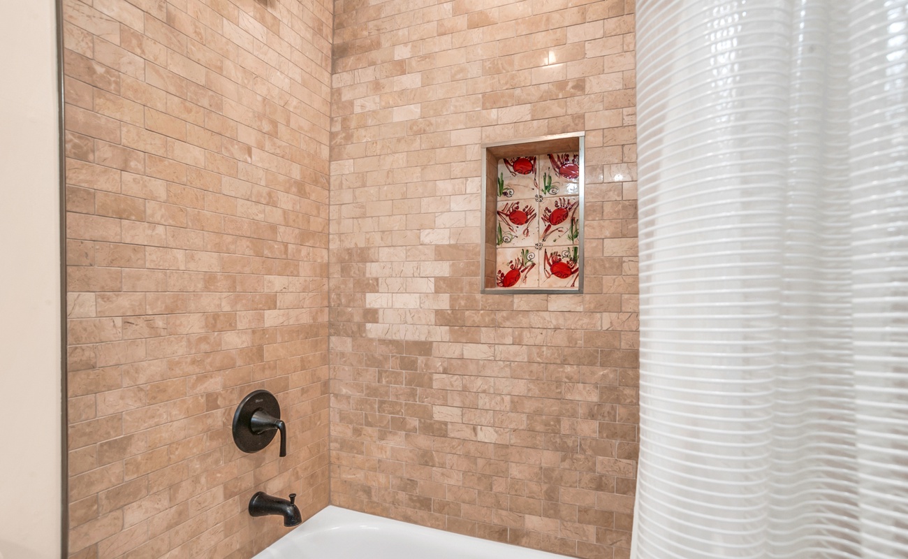 Soak in your beautifully tiled bathtub surrounded by elegant stone-look subway tiles and charming ceramic art details.