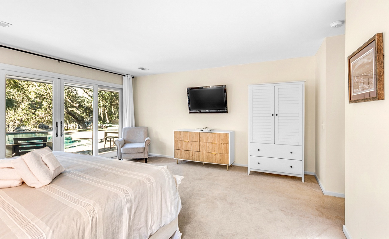 Your spacious bedroom features a comfortable seating area and TV for relaxation, with garden views through sliding doors.