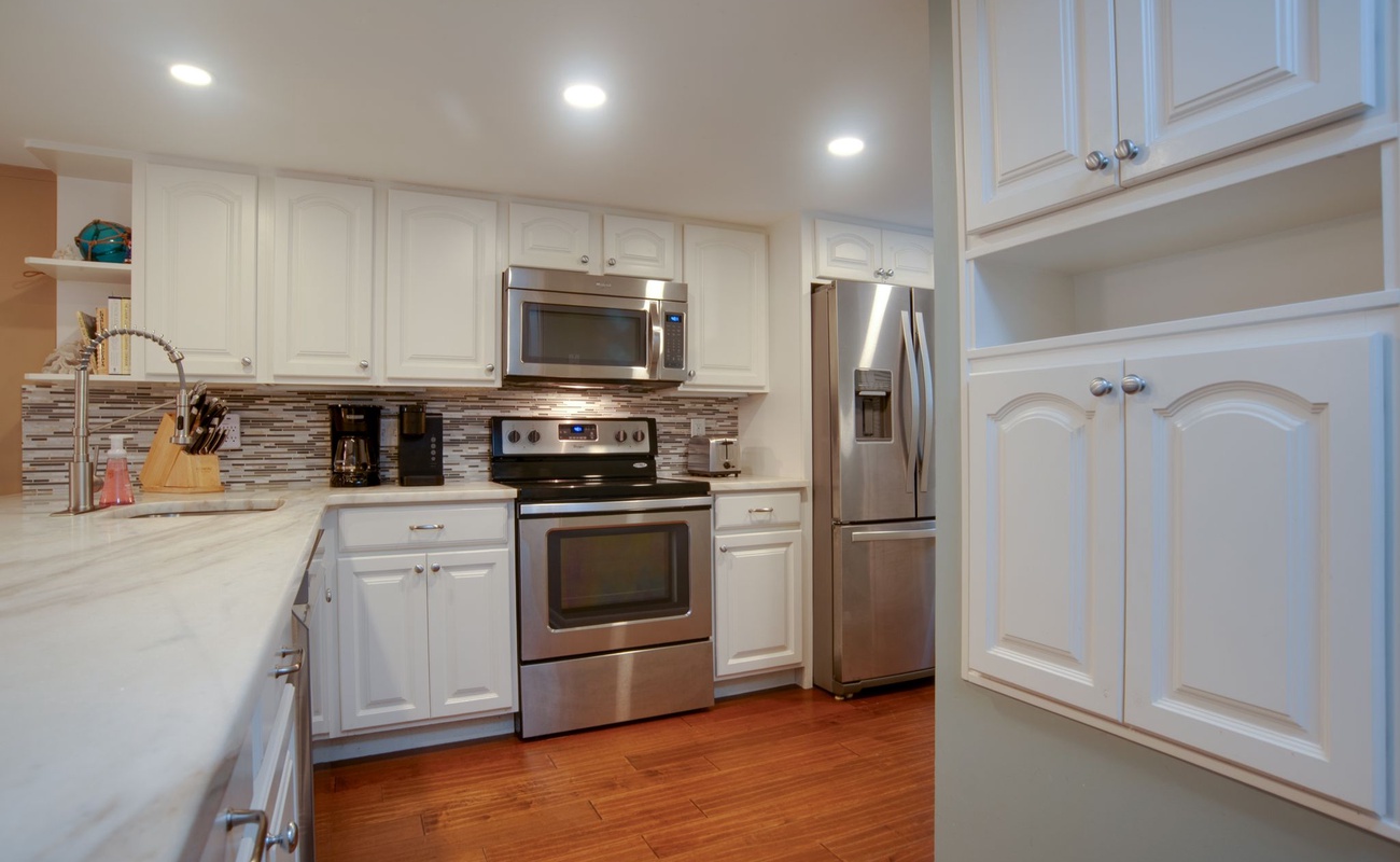 Your fully equipped kitchen features modern stainless steel appliances and elegant white cabinetry, perfect for preparing meals during your stay.