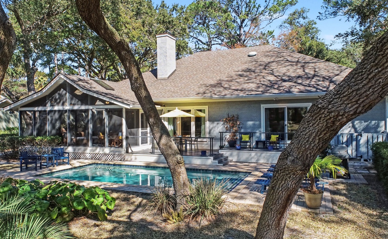 Private oasis featuring a sparkling pool surrounded by mature trees and comfortable outdoor seating for your perfect getaway.