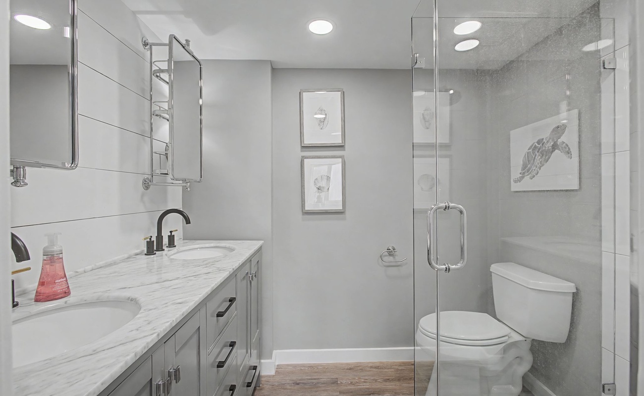 Enjoy your marble countertops and sleek glass shower in this beautifully renovated bathroom with modern gray tones.