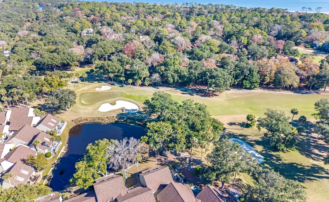 Aerial view showcasing the property's prime location overlooking championship golf greens with ocean views beyond the coastal forest.