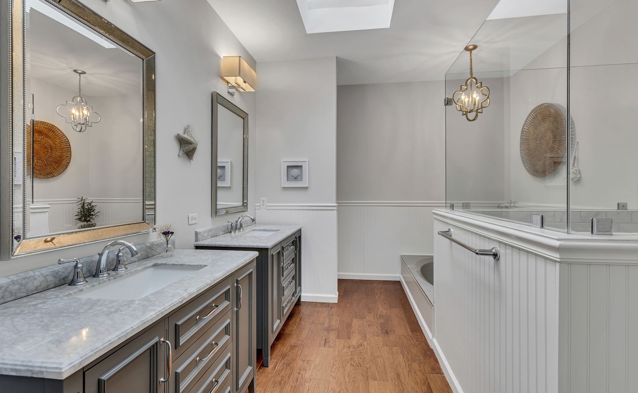 Pamper yourself in this luxurious master bathroom with dual vanities, marble countertops, and elegant pendant lighting creating your perfect retreat.