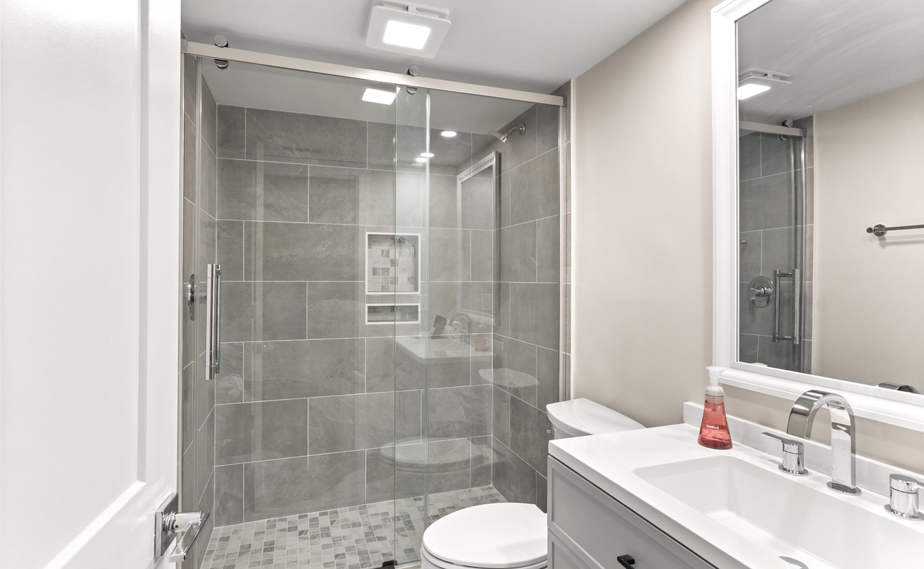 Step into your sleek modern bathroom with a spacious walk-in shower featuring elegant gray tile and glass doors for a spa-like experience.