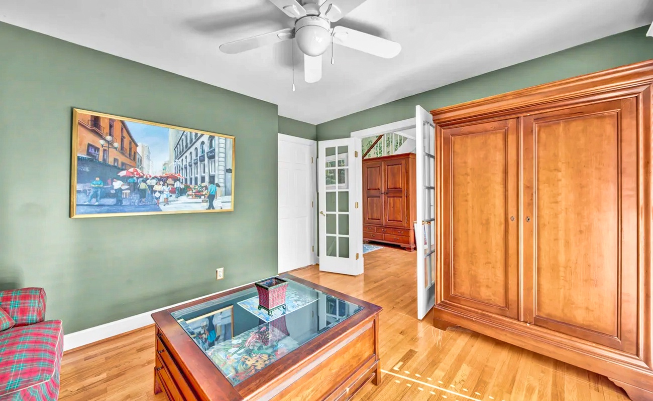 Relax in this charming room with sage-green walls, gleaming hardwood floors, and classic furnishings that create a welcoming atmosphere.