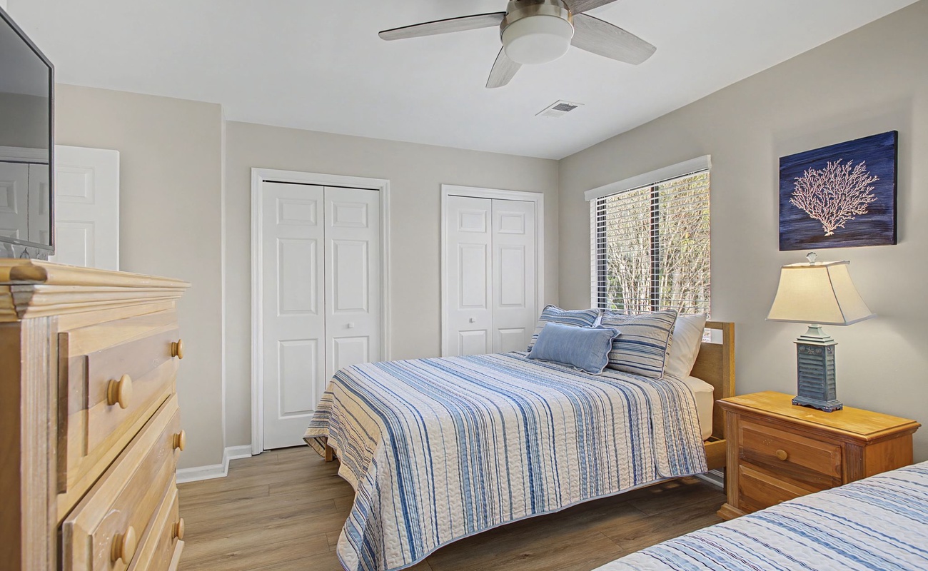Drift off peacefully in your cozy bedroom with coastal blue linens and gentle ceiling fan breeze.