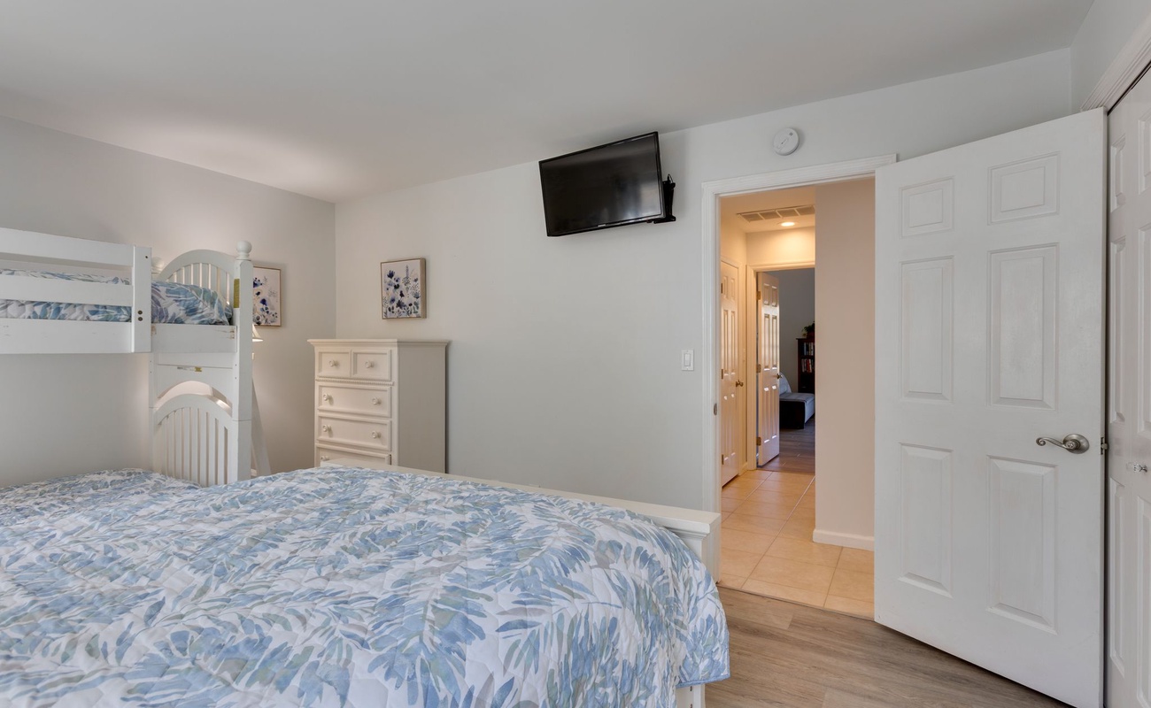 Your comfortable bedroom features a cozy bunk bed and queen bed with tropical-themed bedding, perfect for families.