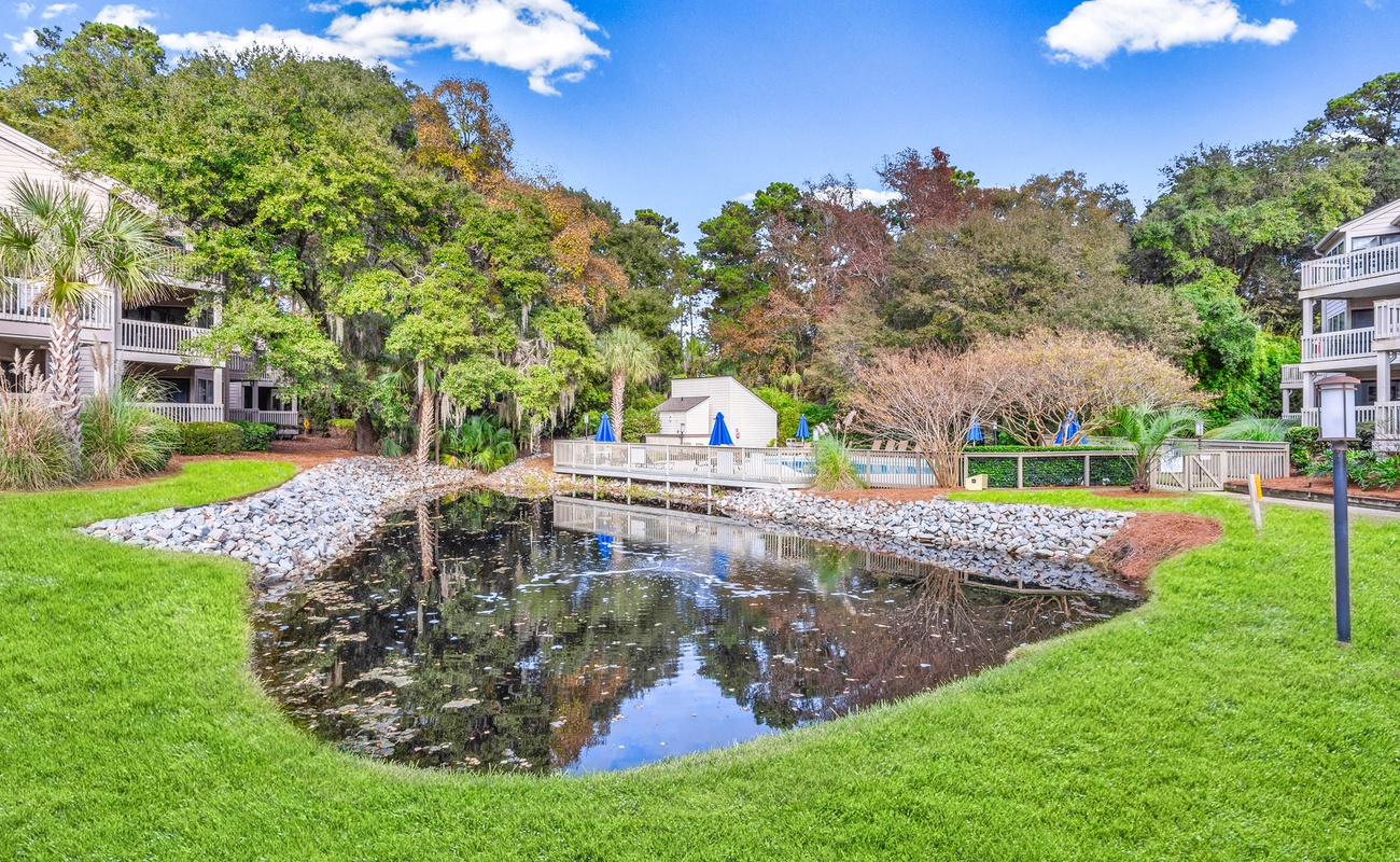 Scenic resort grounds feature a peaceful water feature surrounded by lush landscaping and mature trees.
