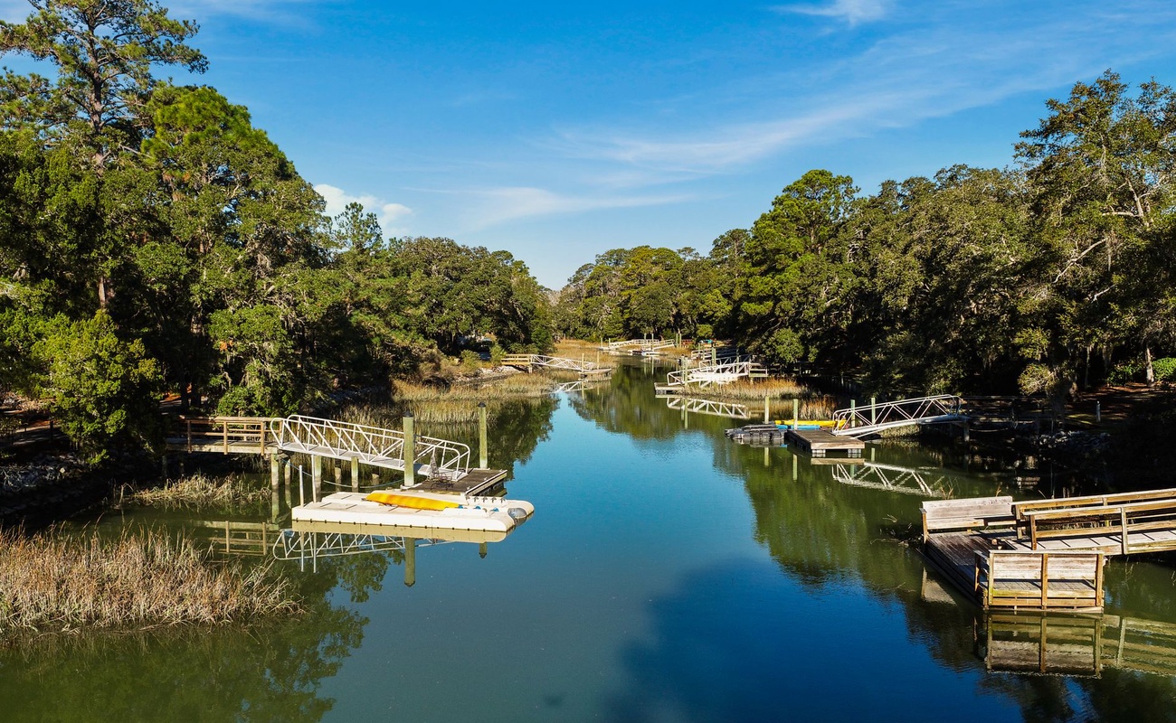 Serene waterway lined with private docks and lush trees, offering peaceful boating access and natural beauty in the surrounding area.