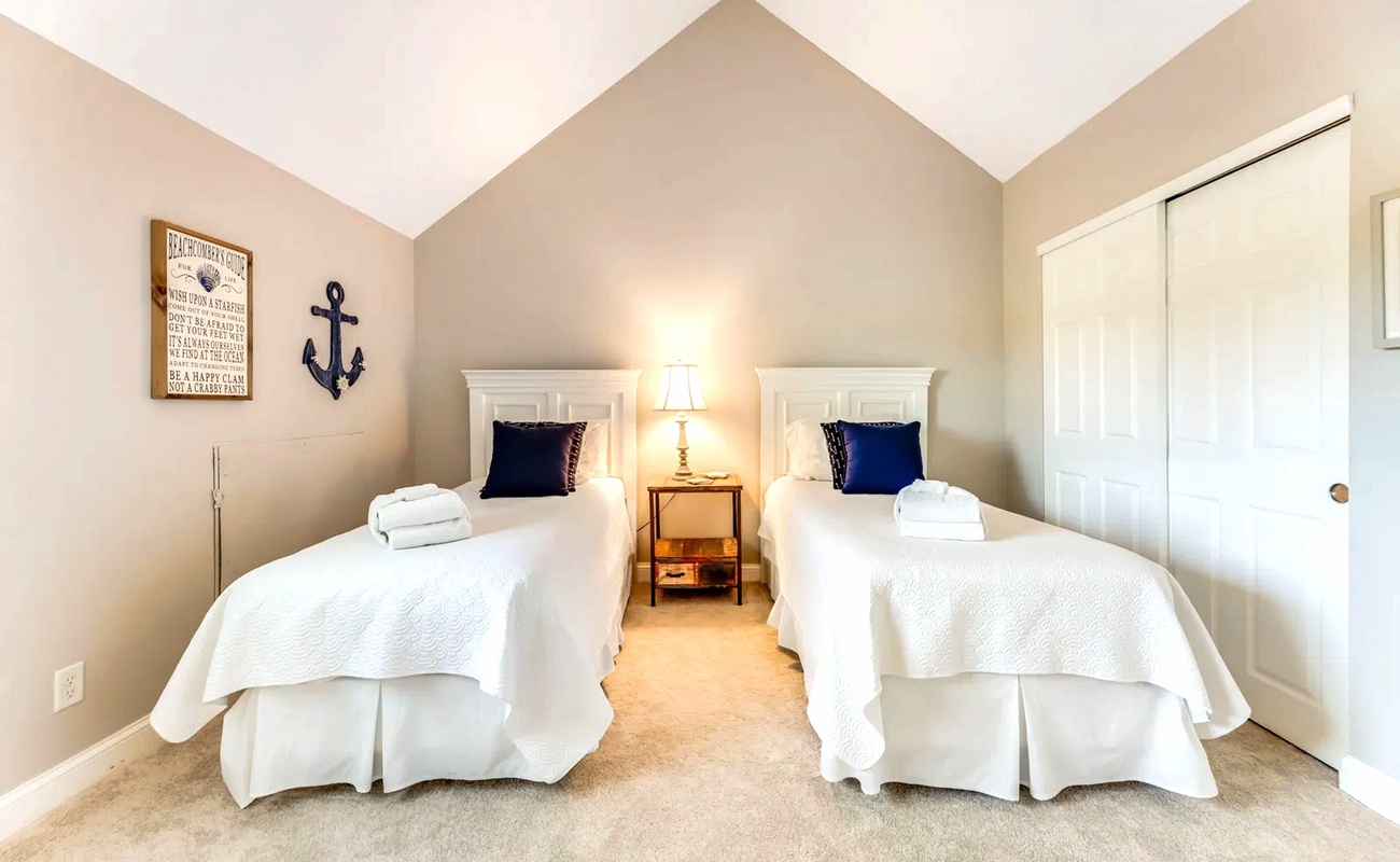Two crisp twin beds await with nautical charm, plush towels ready for your comfort in this serene coastal retreat.