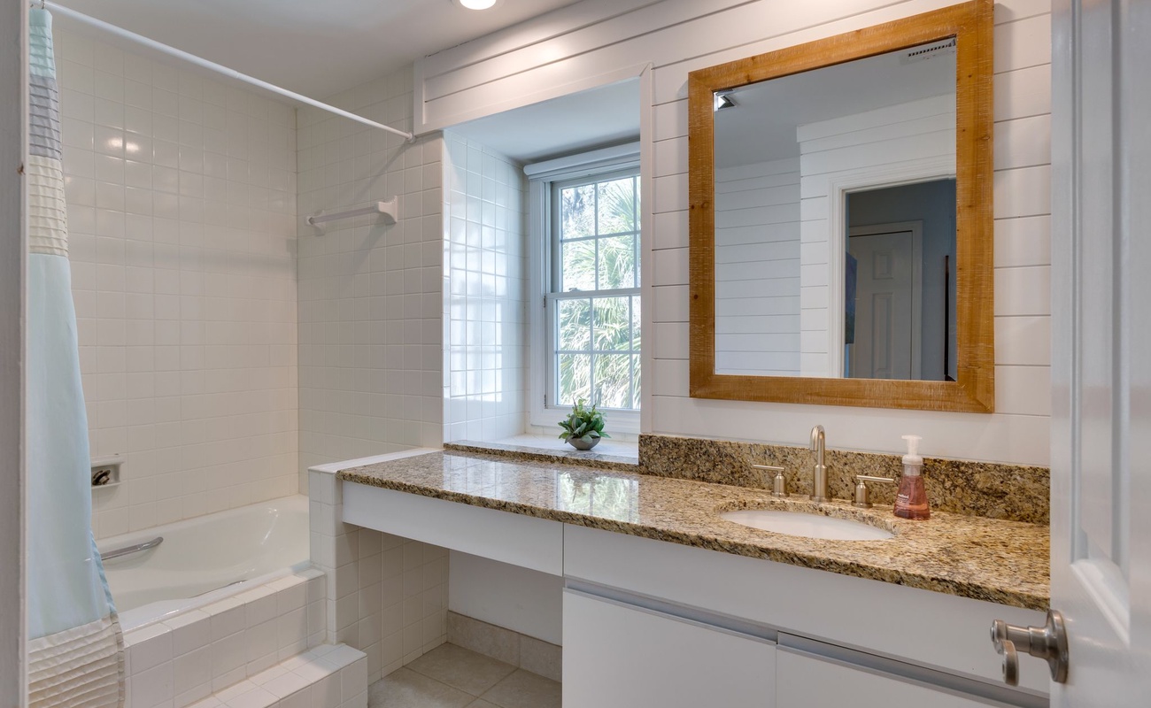 Refresh in your bright, modern bathroom featuring granite counters, elegant shiplap walls, and a relaxing tub-shower combo.