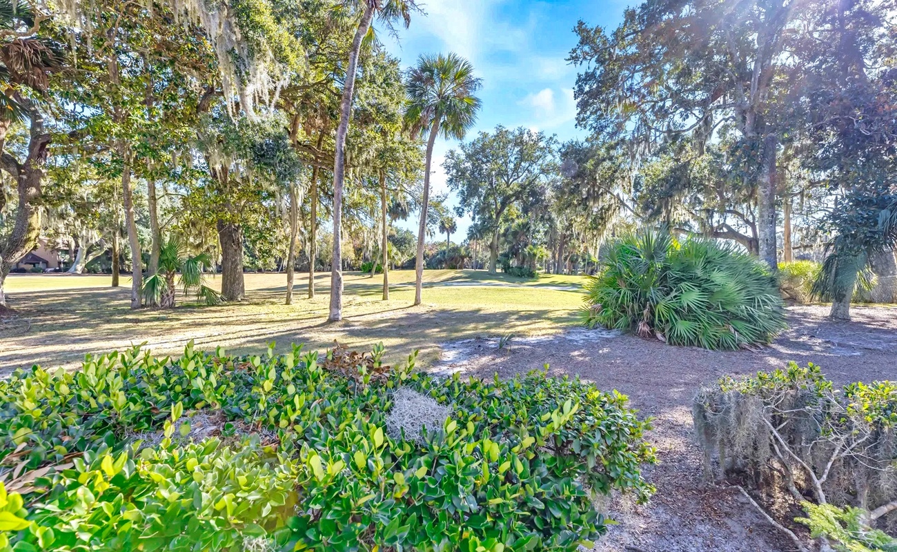 Peaceful landscaped grounds feature mature oak trees draped with Spanish moss and tropical palms creating natural shade throughout the property.