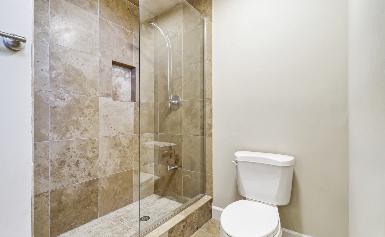 Your private bathroom features elegant travertine tiles and a spacious walk-in shower with modern glass doors for a luxurious retreat.