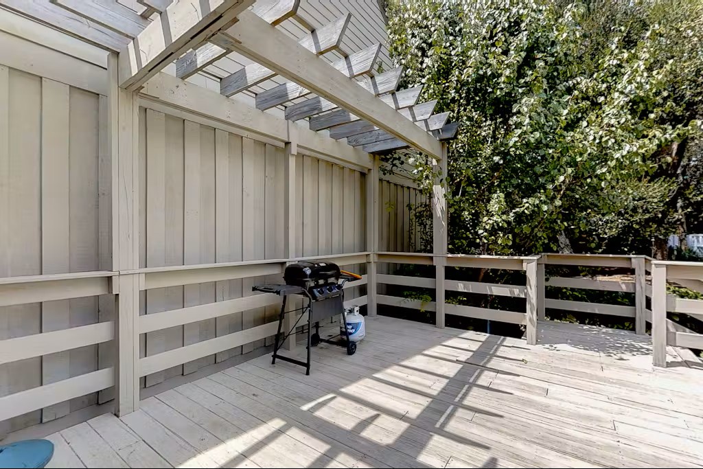 Your private deck awaits with a gas grill ready for outdoor cooking, surrounded by natural wood and dappled sunlight.