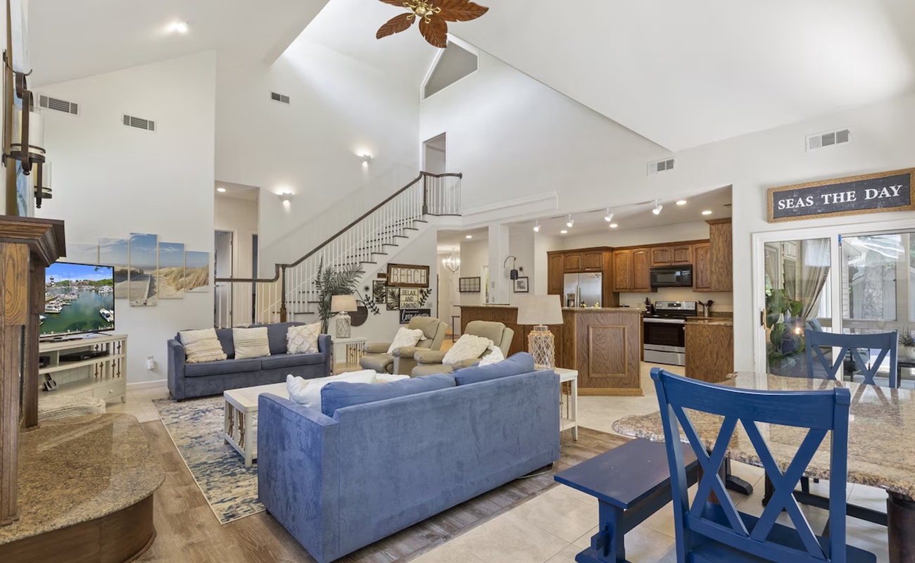 Relax in your spacious open-concept living room with soaring ceilings, coastal blue furnishings, and a fully equipped kitchen ready for your culinary adventures.