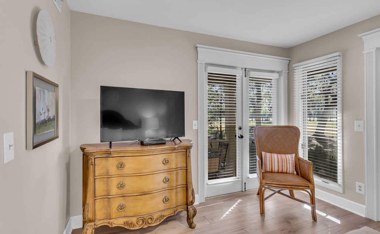 Unwind in your bright corner retreat with classic furnishings, modern TV, and peaceful garden views through elegant French doors.