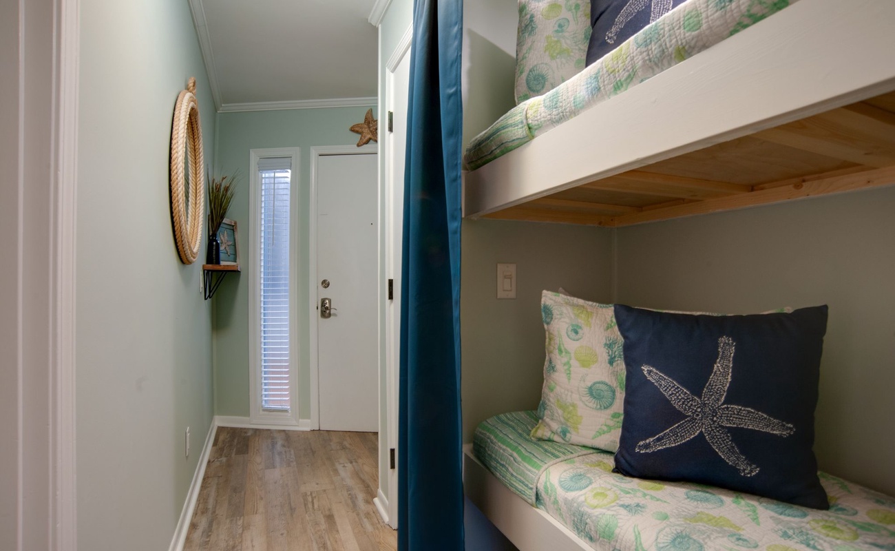 Cozy bunk beds with ocean-themed linens create your perfect coastal retreat, complete with privacy curtains for peaceful sleep.