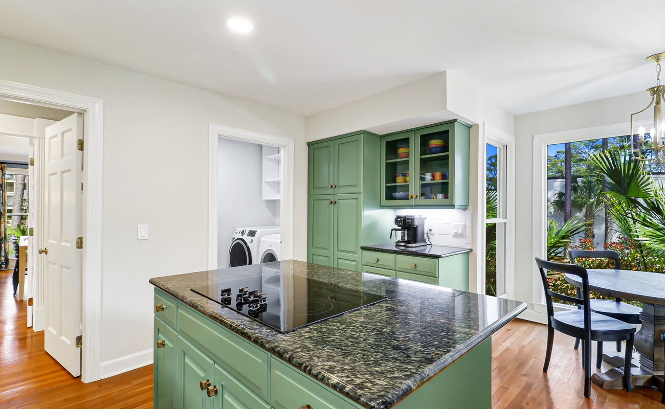 Functional kitchen island with granite counters and sage-green cabinetry creates the perfect space for meal prep and morning coffee.