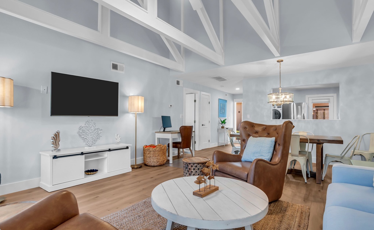 Unwind in this inviting coastal living area where vaulted ceilings and exposed beams create an airy, open feel. Supple leather chairs offer the perfect place to settle in after a sun-filled beach day