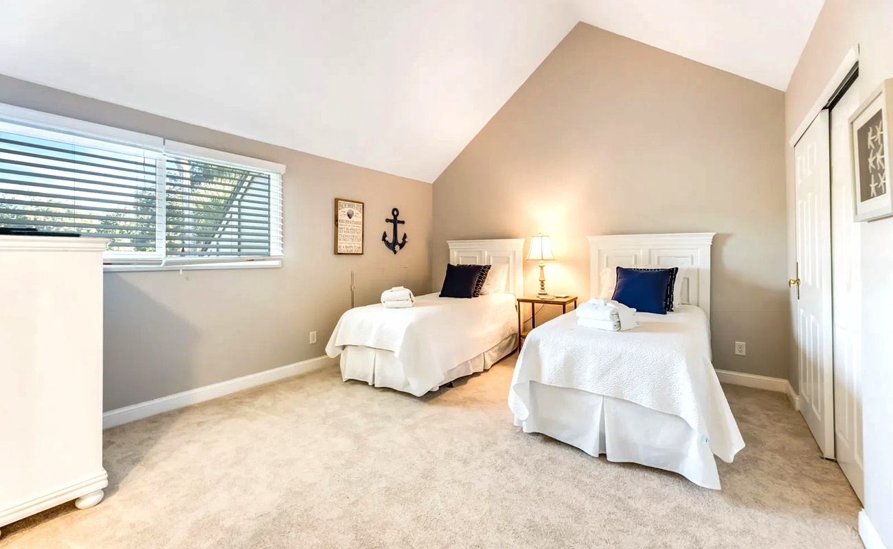 Rest peacefully in your twin bedroom featuring crisp white linens, nautical touches, and natural light streaming through windows.