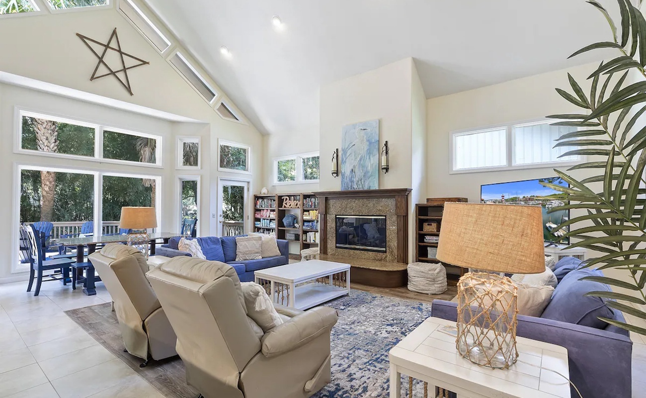 Your spacious living room welcomes you with soaring ceilings, natural light flooding through expansive windows, and plush seating around a cozy fireplace.