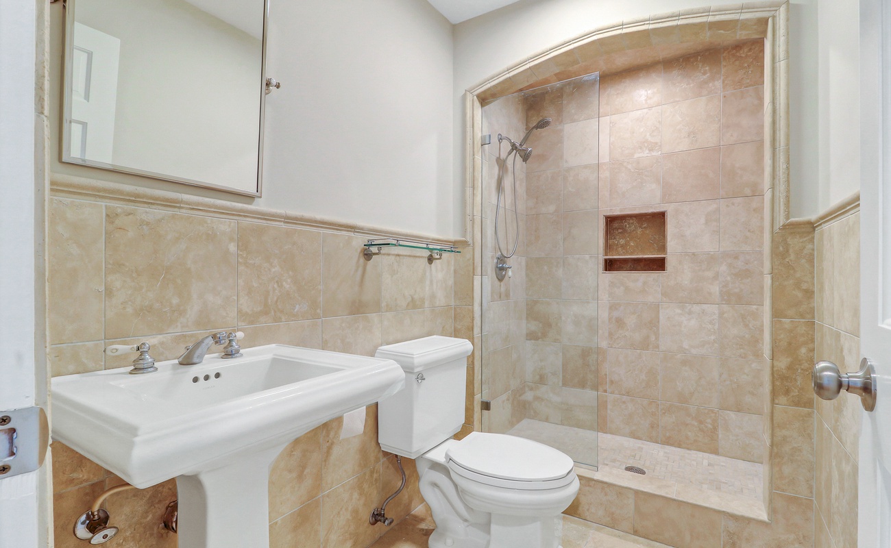 Your elegant bathroom features warm travertine tiles and a spacious glass-enclosed shower for ultimate relaxation.