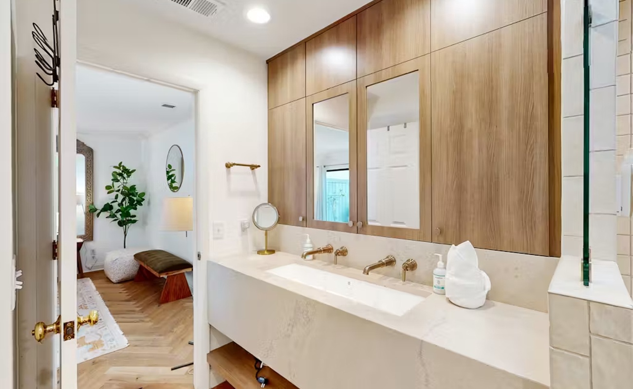Unwind in your sleek spa-inspired bathroom featuring warm wood cabinetry, pristine marble counters, and luxurious dual vanity perfect for your morning routine.