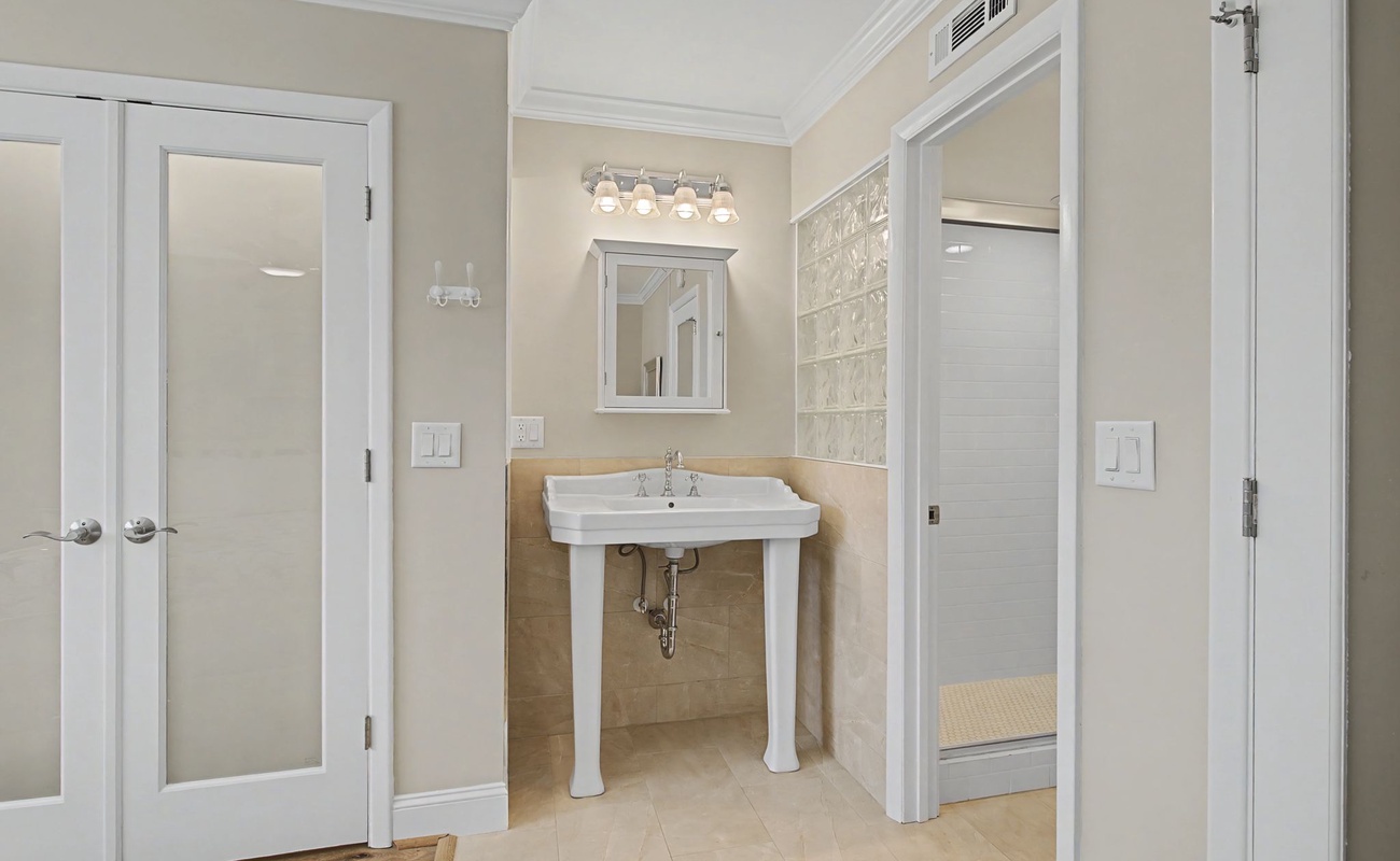 Your elegant bathroom features a classic pedestal sink and spacious glass shower with luxury finishes.