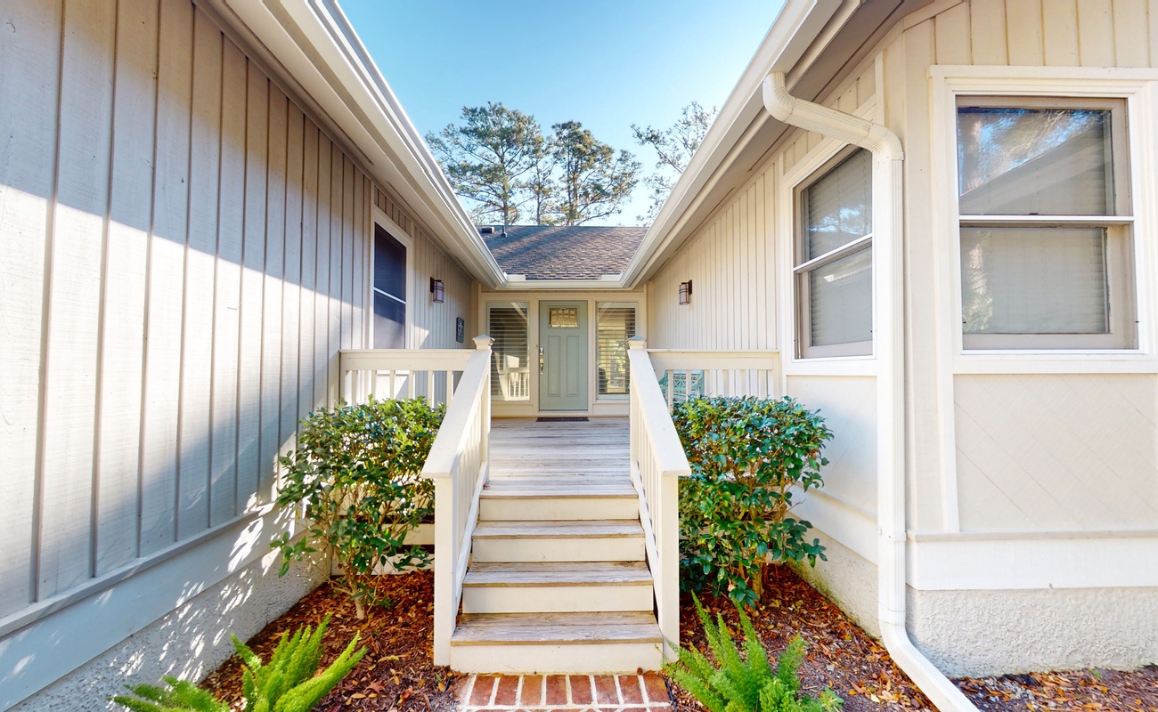 Clean lines and coastal charm welcome guests to this beautifully maintained property entrance with thoughtful landscaping and bright design.