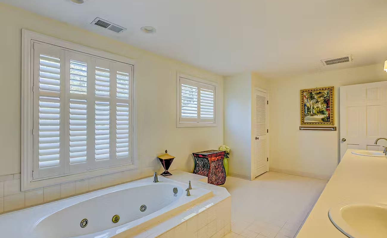 Soak in your private jetted tub beneath elegant plantation shutters, where warm afternoon light creates the perfect spa-like sanctuary for pure relaxation.