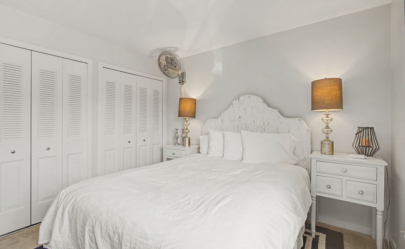 Sink into crisp white linens and let the warm lamp glow create your perfect bedtime ambiance in this serene retreat.