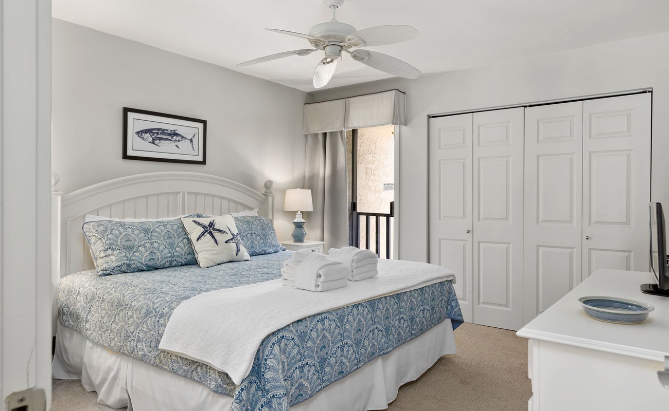 Your coastal-themed bedroom awaits with fresh ocean blues, soft linens, and a gentle ceiling fan for peaceful seaside slumber.